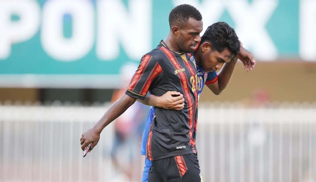 Pemain belakang tim sepakbola putra NTT Frengky Missa membantu  pemain  tim sepakbola putra Papua Hermando Walilo yang mengalami cedera pada laga Grup A PON XX Papua 2021. (Foto: PB PON XX Papua/Chaarly Lopulua)