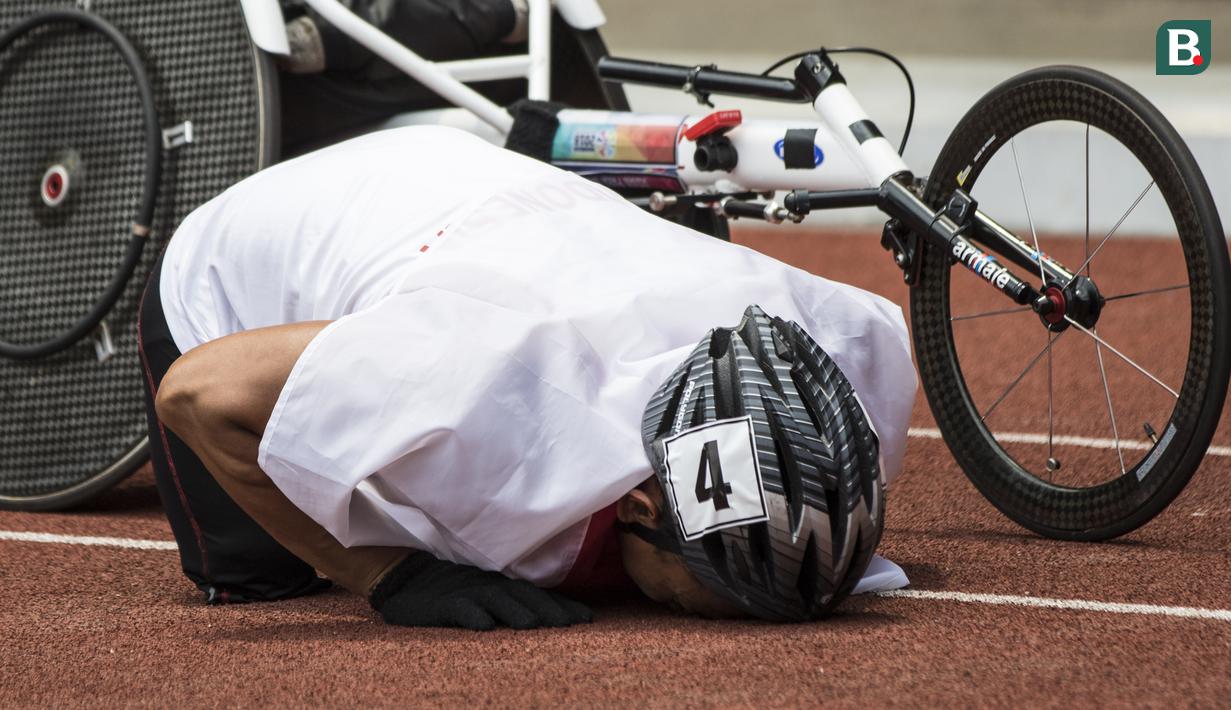 Pebalap kursi roda Indonesia, Jaenal Aripin, sujud syukur usai meraih medali perak pada Asian Para Games cabang atletik nomor balap kursi roda 200 meter T 54 di SUGBK, Jakarta, Jumat (12/10). (Bola.com/Vitalis Yogi Trisna)