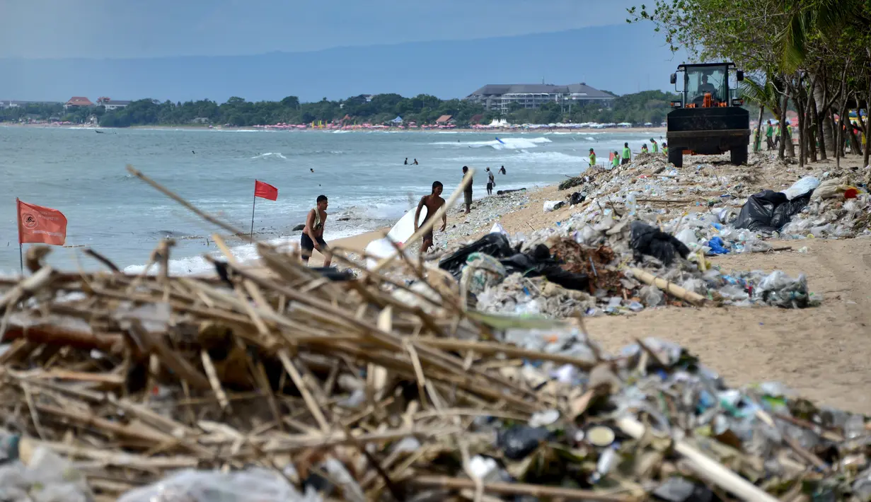 Pekerja menggunakan alat berat membersihkan sampah dan sampah plastik saat pembersihan pantai Kuta dekat Denpasar di pulau wisata Bali (6/1/2021). (AFP/Sonny Tumbelaka)