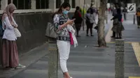 Seorang wanita memakai masker pelindung  sambil bermain ponsel di Jakarta, Rabu (17/7/2019). Dinkes DKI menyarankan masyarakat untuk menggunakan masker saat beraktivitas untuk mencegah dampak polusi udara pada tubuh. (Liputan6.com/Faizal Fanani)