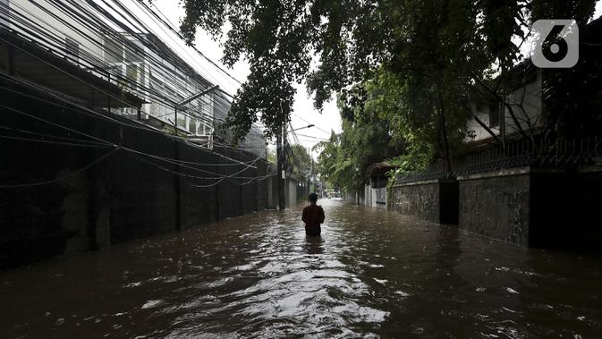 Warga melintasi banjir di Jalan Hang Lekir, Kebayoran Lama, Jakarta Selatan, Rabu (1/1/2020). Banjir tersebut disebabkan karena tingginya intensitas hujan yang mengguyur sejak Selasa (31/12/2019). (Liputan6.com/Johan Tallo)