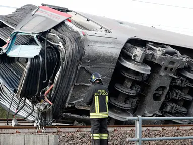 Seorang petugas pemadam kebakaran memeriksa gerbong kereta yang tergelincir, dekat Lodi, Italia utara, Kamis (6/2/2020). Kereta berkecepatan tinggi itu keluar dari rel hingga menewaskan sedikitnya dua orang dan sekitar 30 lainnya luka dalam insiden itu. (AP/Antonio Calanni)