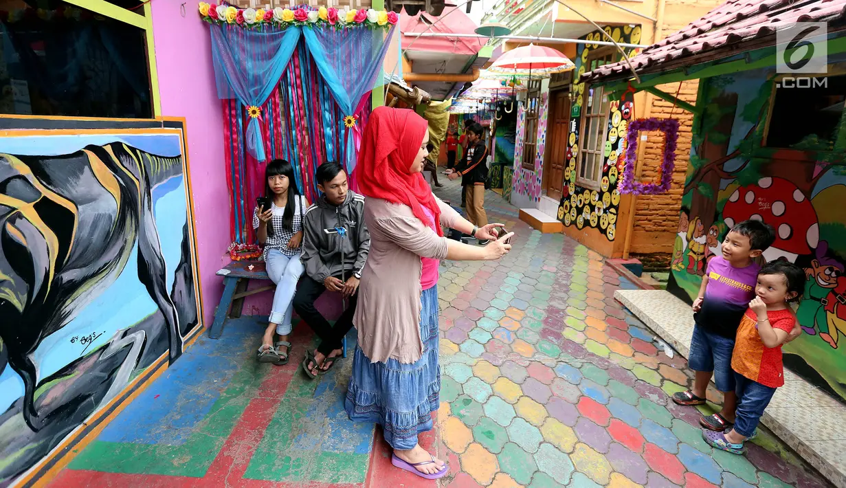Seorang ibu memfoto anaknya di depan mural di Kampung Warna-warni Jodipan dan Kampung Tridi (3D) di pinggir Sungai Brantas, Tumenggungan Ledok, Blimbing, Kota Malang, Jawa Timur (29/7). (Liputan6.com/Johan Tallo)