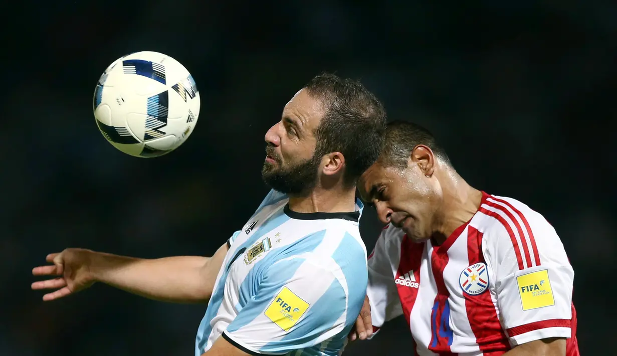 Pemain Argentina Gonzalo Higuan berebut bola dengan pemain Paraguay Paulo Da Silva pada pertandingan kualifikasi Piala Dunia 2018 di Stadion Mario Kempes, Cordoba, Argentina (11/10). (REUTERS/Marcos Brindicci)