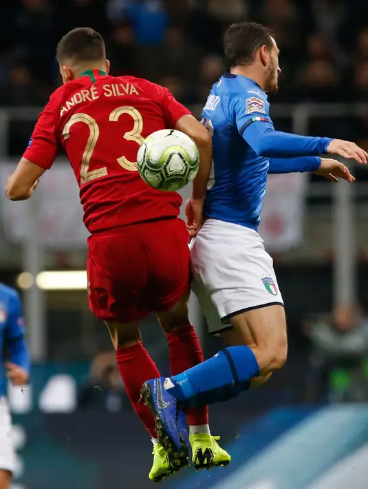 Striker Portugal, Andre Silva berebut bola udara dengan gelandang Italia,  Alessandro Florenzi selama pertandingan UEFA Nations League di Stadion San Siro di Milan (17/11). Italia bermain imbang 0-0 atas Portugal. (AP Photo/Antonio Calanni)
