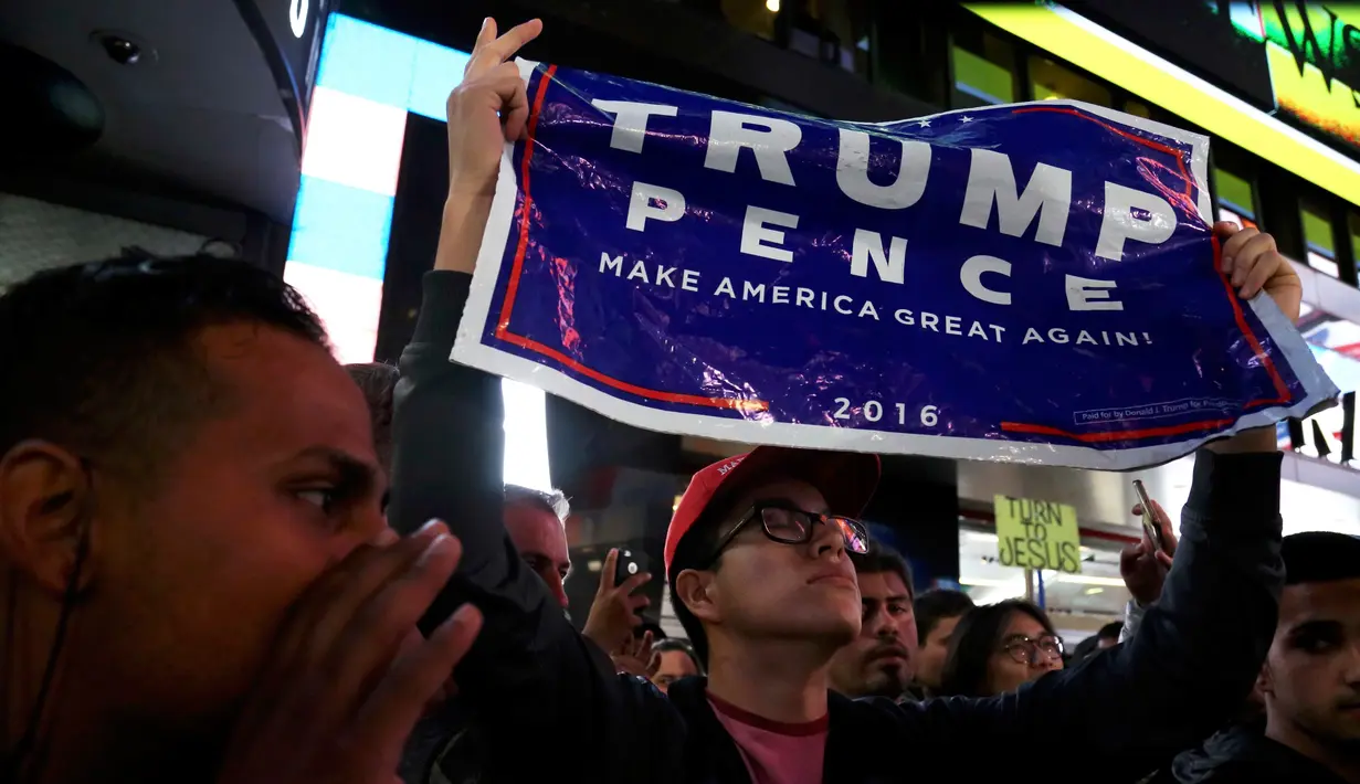 Seorang pendukung capres dari Partai Republik Donald Trump membentangkan spanduk saat perhitungan suara Pilpres AS 2016 di Manhattan, New York, AS, (8/11). (REUTERS/Bria Webb)