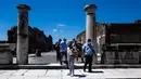 Orang-orang dengan mengenakan masker mengunjungi situs arkeologi Pompeii seusai kebijakan lockdown untuk mengendalikan penyebaran Covid-19 di Italia, Selasa (26/5/2020). Salah satu situs arkeologi paling terkenal di dunia ini dibuka kembali untuk umum pada 26 Mei. (Tiziana FABI / AFP)