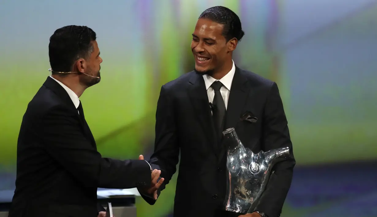 Bek Liverpool Virgil van Dijk (kanan) bersalaman sambil memegang piala penghargaan Pemain Terbaik Eropa 2018-2019 selama undian babak grup di Grimaldi Forum, Monako, Kamis (29/8/2019). Virgil van Dijk berhasil mengungguli Lionel Messi dan Cristiano Ronaldo. (AP Photo/Daniel Cole)