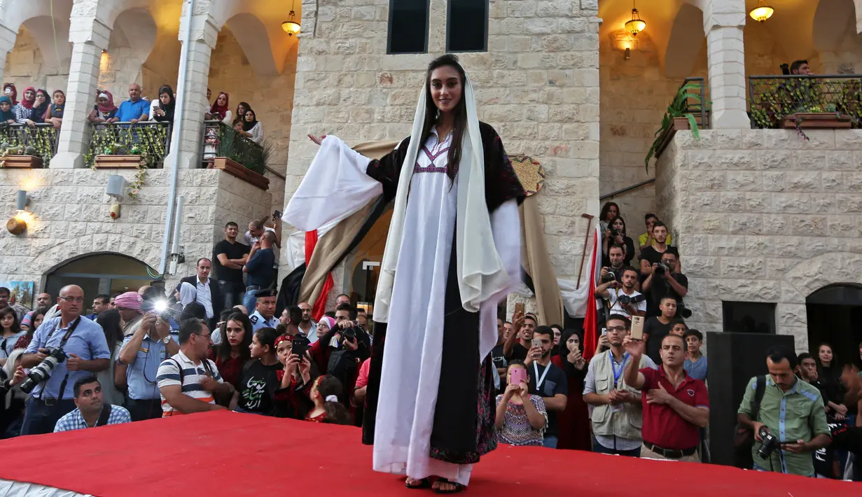 Model berpose di atas catwalk dalam peragaan busana tradisional Palestina di Kota Tua Nablus, Tepi Barat, Palestina, Selasa (22/8). Peragaan busana ini sebagai salah satu upaya untuk melestarikan budaya Palestina. (AFP Photo/Jaafar Ashtiyeh)