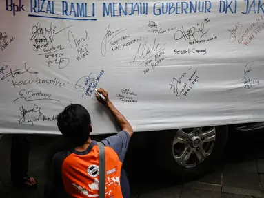 Seorang warga turut memberikan dukungan kepada Rizal Ramli sebagai bakal calon gubernur DKI 2017 dengan menandatangani spanduk, Jakarta, Senin (8/8). Aksi tersebut dilakukan oleh Konferederasi Serikat Pekerja Indonesia (KSPI). (Liputan6.com/Faizal Fanani)