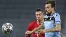 Penyerang Bayern Munchen, Robert Lewandowski dan bek Lazio, Francesco Acerbi berebut bola pada leg kedua babak 16 besar Liga Champions di Allianz Arena, Kamis dinihari WIB (18/3/2021). Munchen menang 2-1 atas tamunya Lazio dan maju ke perempatfinal dengan agregat 6-2. (AP Photo/Matthias Schrader)