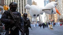 Polisi bersenjata lengkap berjaga ketika balon Olaf melayang di atas kawasan Sixth Avenue selama Parade Macy's Thanksgiving Day di New York, Kamis (22/11). Membelah jalanan kota, Parade Macy's selalu ditunggu setiap tahunnya. (AP/Mary Altaffer)