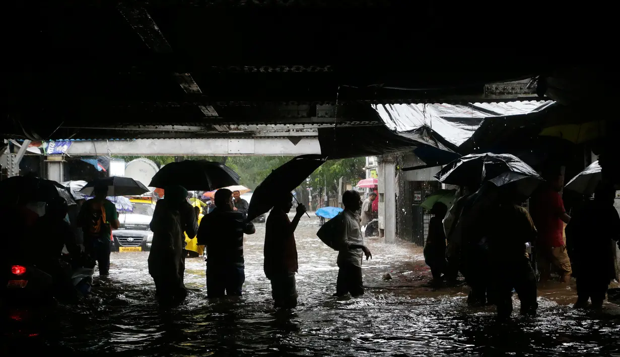 Sejumlah orang menerobos banjir yang merendam jalanan kota Mumbai, India, Selasa (29/8). Hujan lebat diperkirakan terus berlanjut selama 24 jam ke depan dan memaksa ratusan warga untuk tinggal di dalam rumah. (AP Photo/Rajanish Kakade)