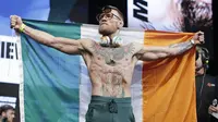 Petarung MMA, Conor McGregor, berpose dengan bendera negaranya saat sesi timbang berat badan di Las Vegas, Jumat (25/8/2017). Keduanya akan bertarung pada Minggu (27/6/2017) di T-Mobile Arena, Las Vegas, Amerika Serikat. (AP/John Locher)