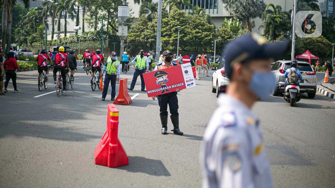 Petugas Dishub dan Satpol PP DKI Jakarta mensosialisasikan protokol kesehatan 3M di kawasan Bundaran HI, Jakarta Pusat, Minggu (8/11/2020). Pemprov DKI Jakarta memastikan masa Pembatasan Sosial Berskala Besar transisi yang berakhir pada hari ini kembali diperpanjang. (Liputan6.com/Faizal Fanani)
