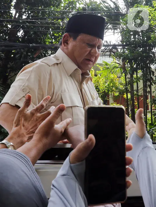 Selama perjalanan dari SDN Jati 03, Jakarta, Presiden Prabowo tampak mengenakan peci hitam dan berdiri sambil membagikan kaos lewat sunroof mobilnya. (Liputan6.com/Herman Zakharia)