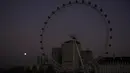 Bulan purnama pertama tahun yang dikenal sebagai Wolf Moon terlihat di belakang London Eye ferris Wheel, di London, Senin (17/1/2022). Wolf Moon atau disebut juga Bulan purnama Serigala adalah sebutan untuk bulan purnama pertama di Januari. (AP Photo/Matt Dunham)