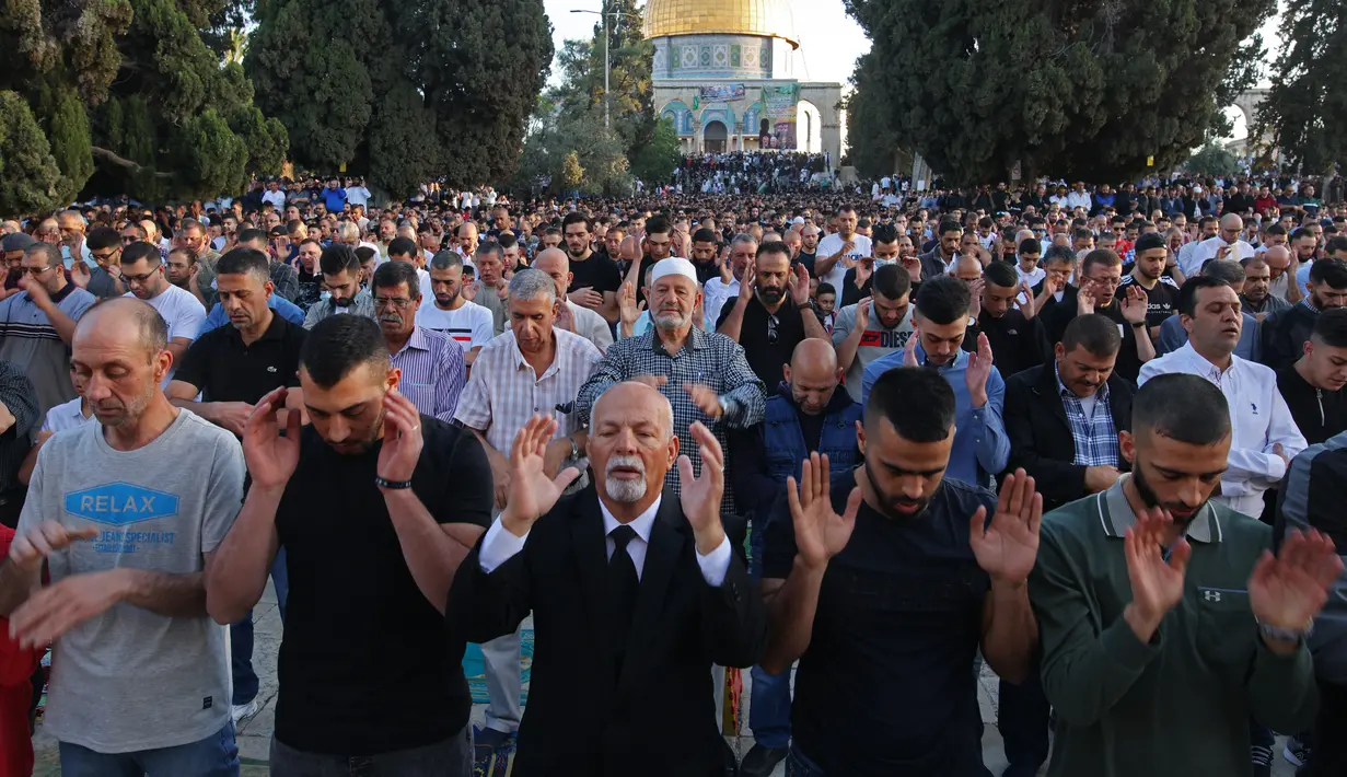 Umat Muslim melaksanakan sholat Idul Fitri di luar masjid Kubah Batu di kompleks masjid Al-Aqsa, Yerusalem Tua (13/5/2021).  Rentetan tembakan roket dari Gaza dan serangan udara Israel yang mematikan sebagai pembalasan. (AFP/Ahmad Gharabli)