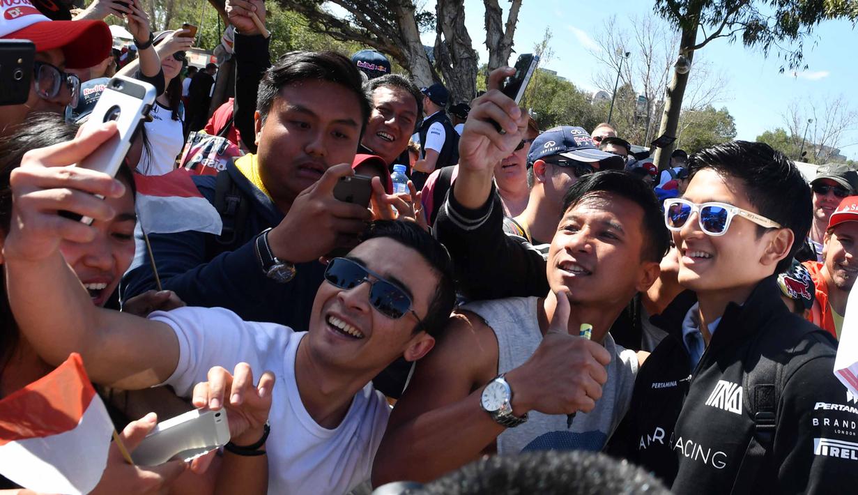 Pebalap Manor F1 Team, Rio Haryanto bertemu fans yang telah menunggu untuk menyaksikan balapan perdana Formula One Australian Grand Prix, Melbourne, Minggu (20/3/2016). (AFP/Paul Crock)