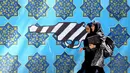 Dua orang wanita berjalan melewati lukisan mural yang menggambarkan pistol di sepanjang dinding bekas Kedutaan Amerika Serikat (AS) di Ibu Kota Teheran, Iran, Sabtu (22/6/2019). (ATTA KENARE/AFP)