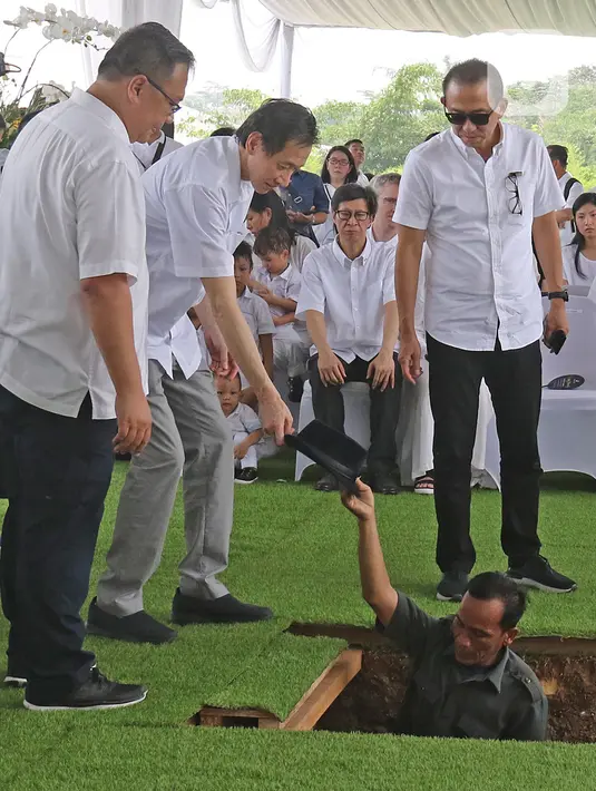 Keluarga meletakkan topi Chairman dan Founder Grup Ciputra Dr (HC), Almarhum Ir. Ciputra ke dalam liang saat prosesi pemakaman di pemakaman keluarga, Jonggol, Bogor, Kamis (5/12/2019). Ciputra meninggal dunia di rumah sakit di Singapura pada 27 November 2019 lalu. (Liputan6.com/Herman Zakharia)