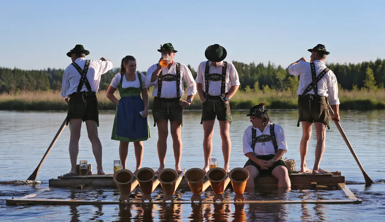 Musisi alphorn, Holdersberger Alp-Traum-Bläser minum bir di atas kapal rakit yang mengapung di danau Elbsee, Jerman selatan (11/6). (AFP PHOTO / DPA / Karl-Josef Hildenbrand / Germany Out)
