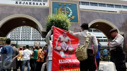 Polisi melihat salah satu poster yang dibawa massa saat menggelar aksi di depan Kejaksaan Agung, Jakarta, Rabu (2/9/2015). Massa menuntut penuntasan perampokan aset BPPN tahun 2003 yang merugikan negara ratusan triliun. (Liputan6.com/Yoppy Renato)