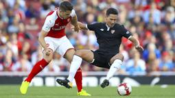 Gelandang Arsenal, Granit Xhaka, berebut bola dengan gelandang Sevilla, Paulo Henrique Ganso pada laga turnamen Piala Emirates yang berlangsung di Stadion Emirates, Minggu (30/7/2017). Arsenal takluk 1-2 dari Sevilla. (AP/John Walton)