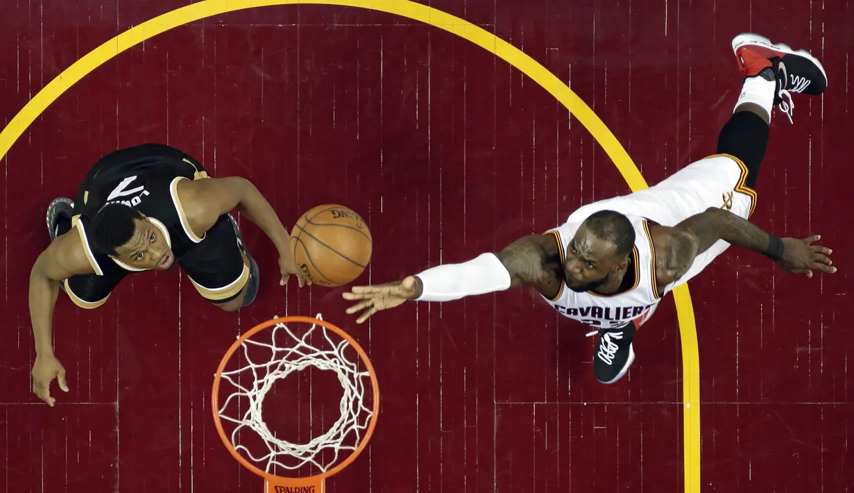 Aksi LeBron James (kanan) memasukan bola melewati adangan pemain Toronto Raptors, Kyle Lowry pada Game 2 pada semifinal Eastern Conference NBA basketball playoff series di Quicken Loans Arena, (3/5/2017). Cavs menang 125-103. (AP/Tony Dejak)