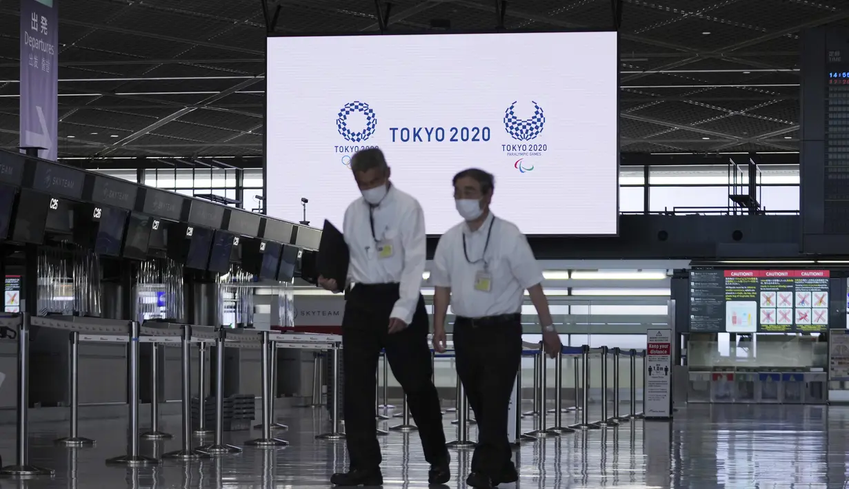 Staf mengenakan masker pelindung untuk membantu mengekang penyebaran virus corona berjalan di area tiket kosong di Bandara Internasional Narita, Tokyo, Selasa siang (1/6/2021). (AP Photo/Eugene Hoshiko)