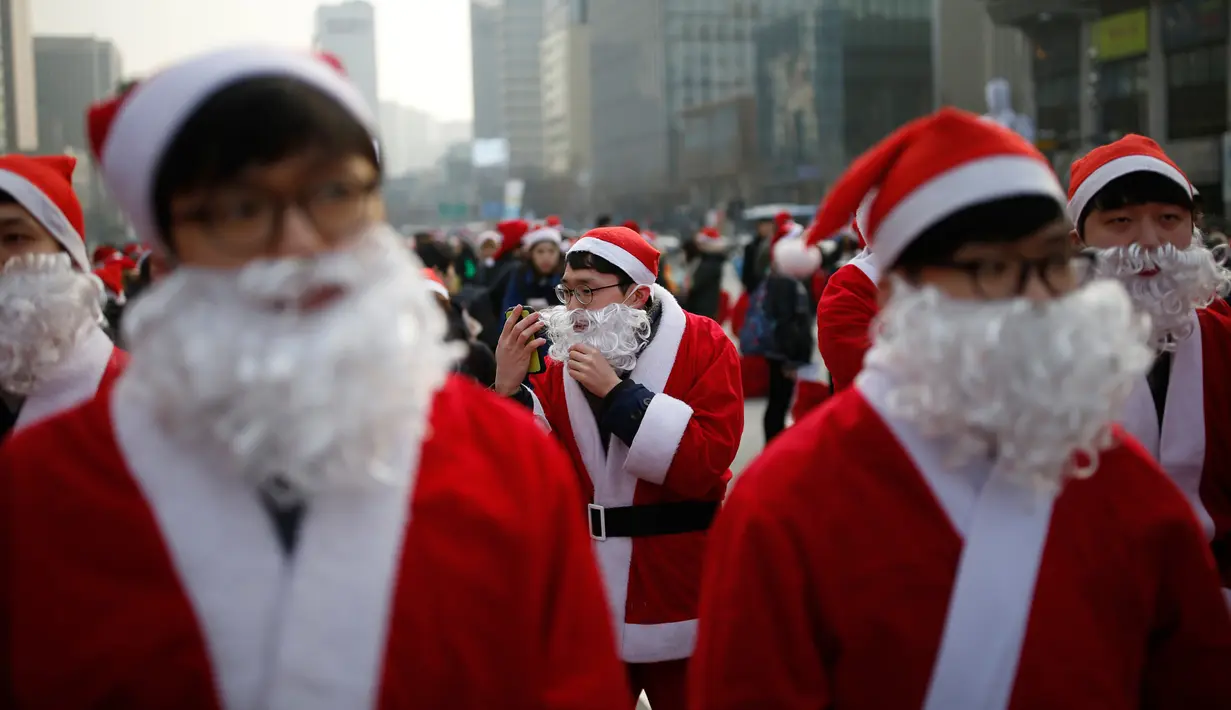 Seorang pria berpakaian seperti Santa Claus merapihkan jengotnya saat acara amal Natal di pusat kota Seoul, Korea Selatan, (24/12/2015). (REUTERS/Kim Hong-Ji)
