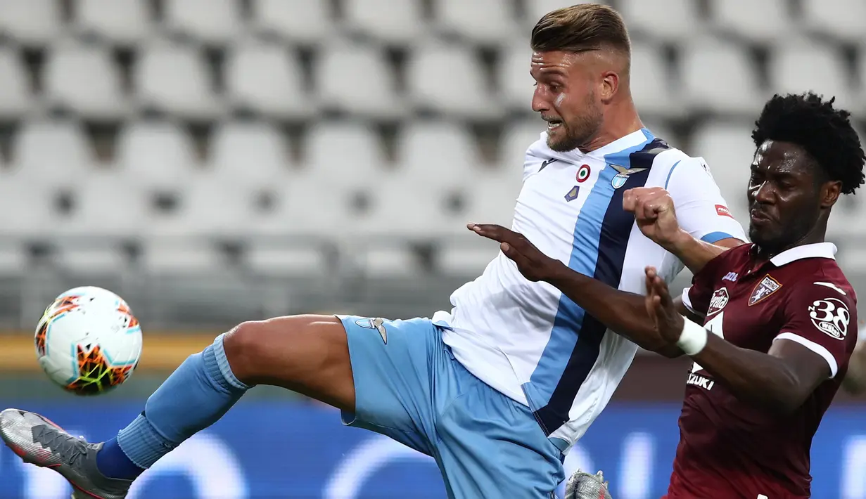 Gelandang Lazio, Sergej Milinkovic-Savic (kiri) berebut bola dengan bek Torino Ola Aina pada pertandingan lanjutan Liga Serie A Italia di stadion Olimpiade di Turin (30/6/2020). Lazio menang tipis atas Torino 2-1. (AFP Photo/Isabella Bonotto)