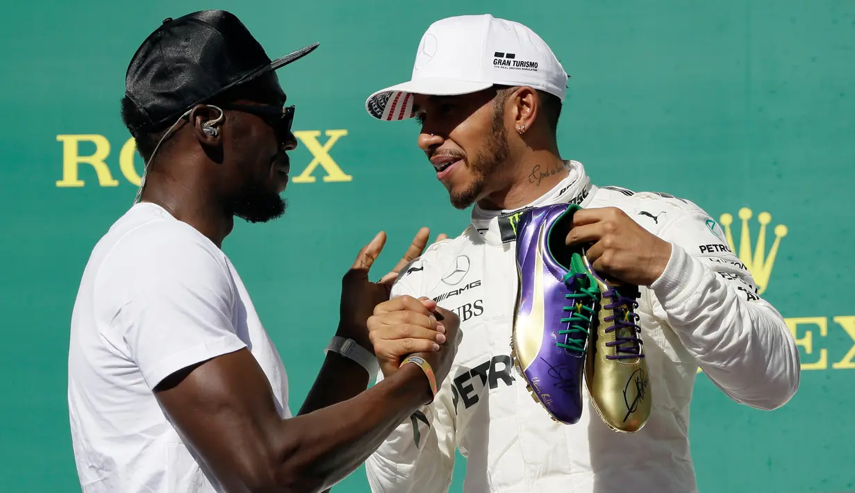 Pembalap Marcedes, Lewis Hamilton mendapat ucapan selamat dari mantan atlet lari cepat asal Jamaika, Usain Bolt di atas podium setelah berhasil memenangi balapan GP Amerika Serikat di Circuit of Americas, Minggu (22/10). (AP Photo / Tony Gutierrez)