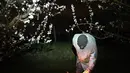 Seorang arborist mengikat lilin antiembun beku untuk melindungi pohon dari embun beku di sebuah kebun karena suhu diperkirakan akan turun di bawah nol derajat celcius dalam beberapa hari ke depan di Westhoffen, Prancis, 6 April 2021. (Frederick FLORIN/AFP)