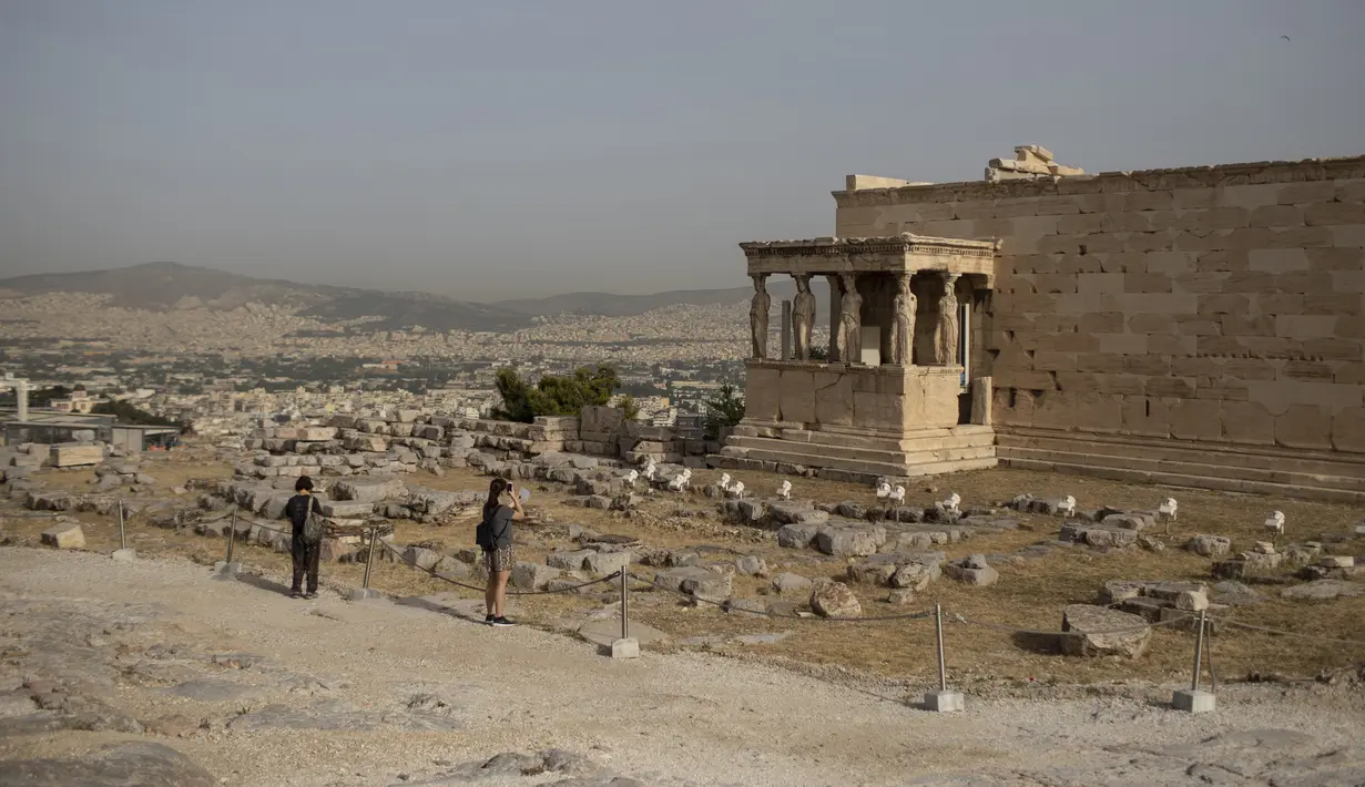 Pengunjung mengambil gambar Patung Caryatid di Kuil Erechtheion, Bukit Acropolis, Athena, Yunani, Senin (18/5/2020). Yunani kembali membuka kota kuno Acropolis serta situs-situs lainnya setelah dua bulan ditutup selama lockdown akibat pandemi virus corona COVID-19. (AP Photo/Petros Giannakouris)