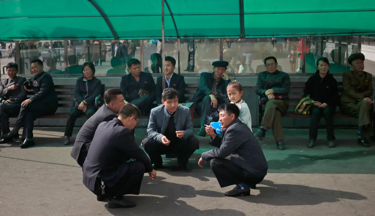 Sejumlah pria Korea Utara berbincang di luar supermarket di pusat kota Pyongyang, Korea Utara, (21/10).  (AP Photo / Dita Alangkara)