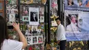 Seorang turis mengambil foto temannya yang berpose dekat memorabilia Putri Diana di luar Istana Kensington, London, Selasa (29/8). Bunga, foto hingga lilin diletakkan di luar Istana untuk mengenang 20 tahun kematian Putri Diana. (AP Photo/Alastair Grant)