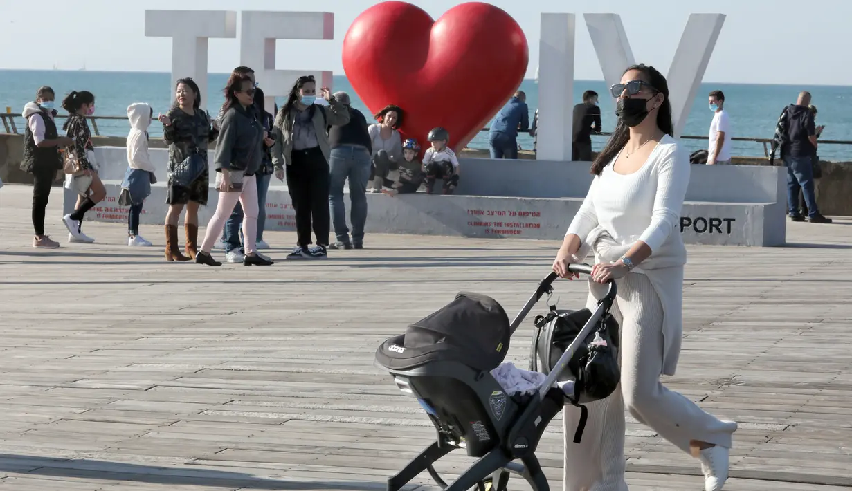 Seorang perempuan mendorong kereta bayi saat menikmati hari yang cerah di Tel Aviv, Israel, pada 26 Desember 2020. Karantina wilayah (lockdown) penuh ketiga akan diberlakukan secara nasional di Israel mulai Minggu (27/12) pukul 17.00 waktu setempat. (Xinhua/JINI/Gideon Markowicz)