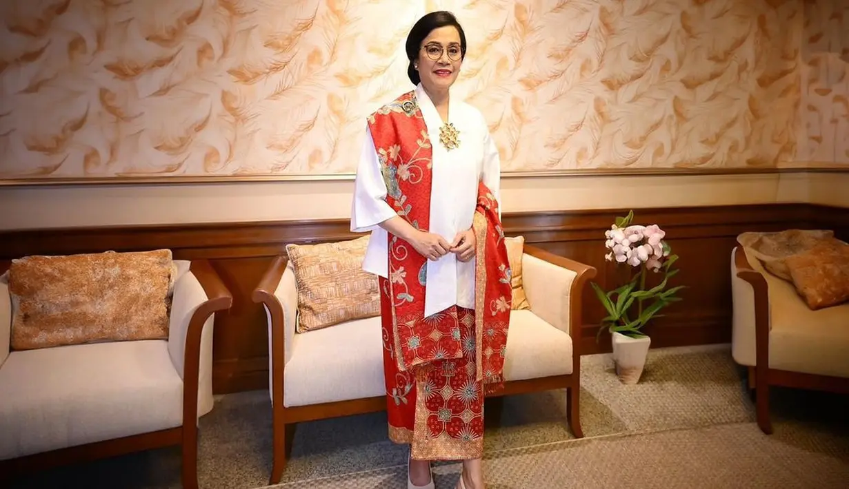 Penampilan elegan Menteri Keuangan Sri Mulyani dibalut kebaya putih polos dengan bros emas di panel tengah. Padu padan kain batik merah sebagai rok dan selendang mempercantik penampilannya secara keseluruhan di sini. [Foto: Instagram/smindrawati]