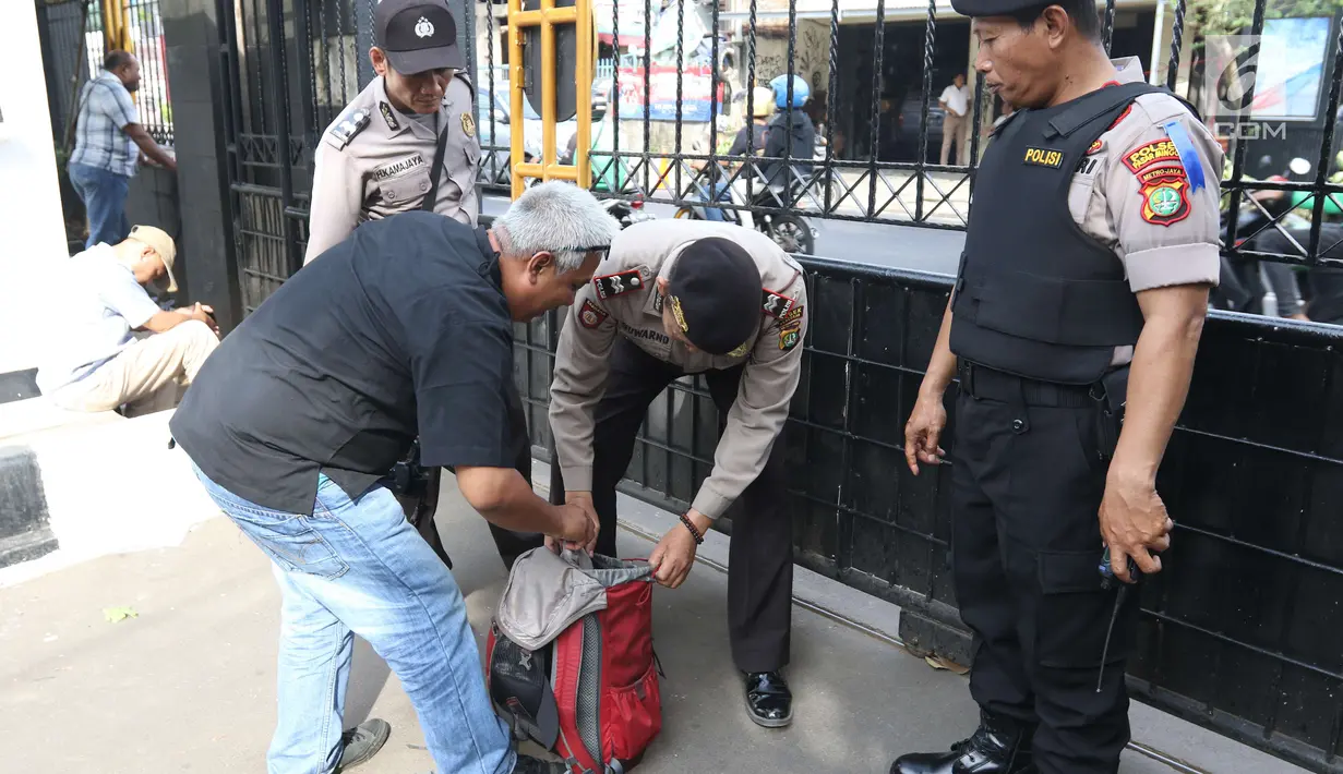 Personel kepolisian mengecek barang bawaan pengunjung yang masuk ke Pengadilan Negeri Jakarta Selatan, Jumat (22/6). Pengamanan berlapis diberlakukan pada sidang pembacaan vonis terdakwa terorisme Aman Abdurrahman. (Liputan6.com/Angga Yuniar)