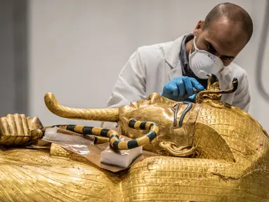 Arkeolog merestorasi sarkofagus atau peti mati emas Firaun Tutankhamun di laboratorium restorasi Grand Egyptian Museum (GEM), Giza, Mesir, Senin (13/4/2020). Firaun Tutankhamun merupakan Raja Mesir Kuno yang memerintah antara tahun 1342-1325 SM. (Khaled DESOUKI AFP)