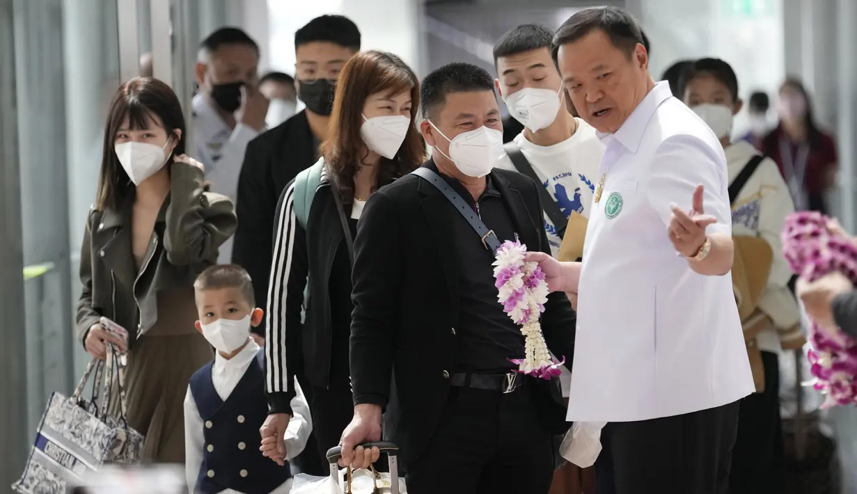 <p>Menteri Kesehatan Masyarakat Thailand Anutin Charnvirakul (kanan) memberikan karangan bunga kepada turis China saat mereka tiba di Bandara Internasional Suvarnabhumi di provinsi Samut Prakarn, Senin (9/1/2023). Thailand berharap dapat menerima sejumlah besar pengunjung dari China lagi setelah Beijing melonggarkan pembatasan perjalanan pada hari Minggu. (AP Photo/Sakchai Lalit)</p>