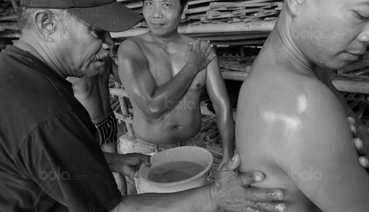 Peserta mengoles badannya dengan minyak sebelum mengikuti kontes binaraga di Desa Jatiwangi, Majalengka, Jawa Barat, (11/8/2017). Kontes yang digelar setiap tahun ini merupakan bagian dari perayaan HUT kemerdekaan RI. (Bola.com/M iqbal Ichsan)