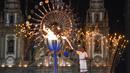 Atlet Brasil, Jorge Alberto Gomes, menyalakan obor Olimpiade dengan latar Gereja Candelaria pada pembukaan Olimpiade Rio 2016 di Rio de Janeiro (5/8/2016). (AFP/Mark Ralston)