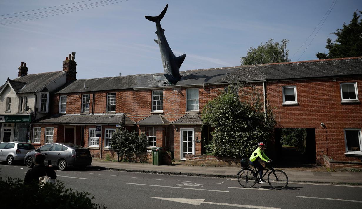 Sebuah patung yang dikenal dengan nama Headington Shark tampak menerobos atap rumah di wilayah pinggiran Oxford, Inggris pada 30 April 2019. Patung hiu unik dibuat tahun 1986 oleh pria asal AS, Bill Heine dari bahan fiberglass dengan panjang 8 meter.  (AP Photo/Matt Dunham)