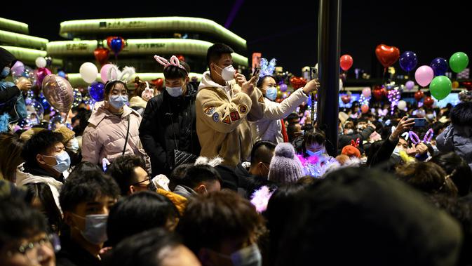 Orang-orang selama hitung mundur Tahun Baru di Wuhan di provinsi Hubei, China (1/1/2021). Setahun yang lalu hari ini, wabah Covid-19 dilaporkan di kota provinsi Hubei, yang kemudian menyebar ke seluruh dunia dan menewaskan lebih dari 1,8 juta orang. (AFP/Noel Celis)