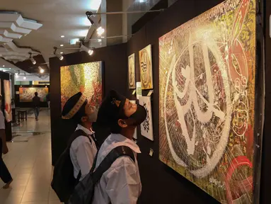 Pengunjung melihat karya pada Pameran Kaligrafi Kontemporer Internasional di Masjid Raya Jakarta Islamic Center, Jakarta, Senin (18/4/2022). Pameran digelar dalam rangkaian peringatan Nuzulul Quran itu menghadirkan lebih dari 100 karya seniman kaligrafi dari 26 negara. (Liputan6.com/Herman Zakharia)