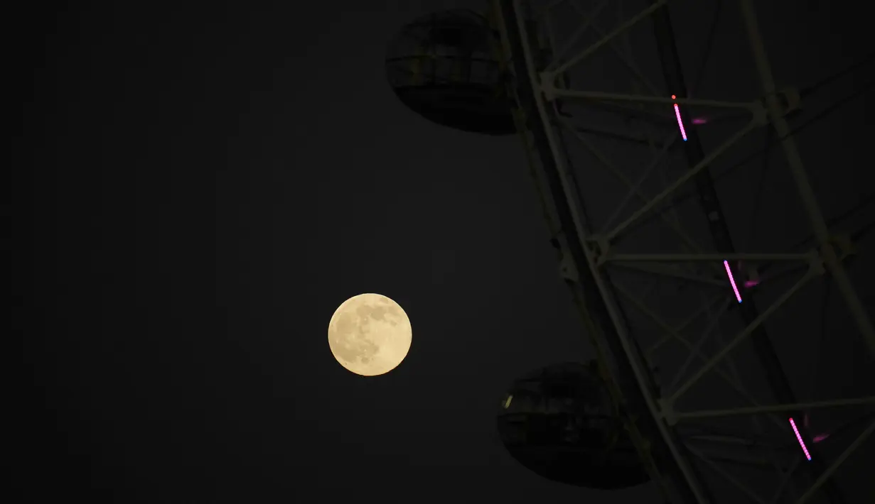 Bulan purnama pertama tahun yang dikenal sebagai Wolf Moon terlihat di belakang London Eye ferris Wheel, di London, Senin (17/1/2022). Wolf Moon atau disebut juga Bulan purnama Serigala adalah sebutan untuk bulan purnama pertama di Januari. (AP Photo/Matt Dunham)