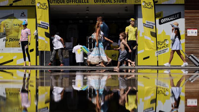 Orang-orang dengan masker melintasi toko resmi Tour de France 2020 di kota Nice, French Riviera, Rabu (26/8/2020). Ajang balap sepeda lintas kota di Prancis ini akan dimulai dari kota Nice pada 29 Agustus hingga 20 September di bawah bayang-bayang 'gelombang kedua' COVID-19. (Kenzo Tribouillard/