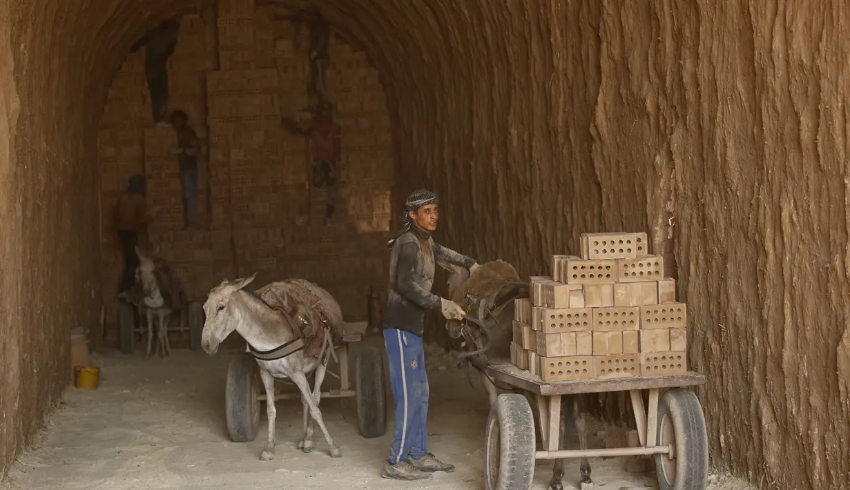 Pria bekerja di pabrik batu bata di pabrik batu bata di pinggiran tenggara Baghdad Nahrawan, Irak, Kamis (24/5/2021).  Para pekerja bekerja 12 jam sehari dengan upah sekitar USD$ 15. (AP Photo/Hadi Mizban)